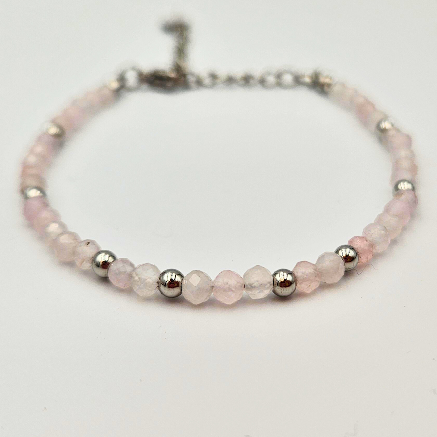Armband van facetgeslepen rozenkwarts afgewerkt met zilverkleurig stainless steel