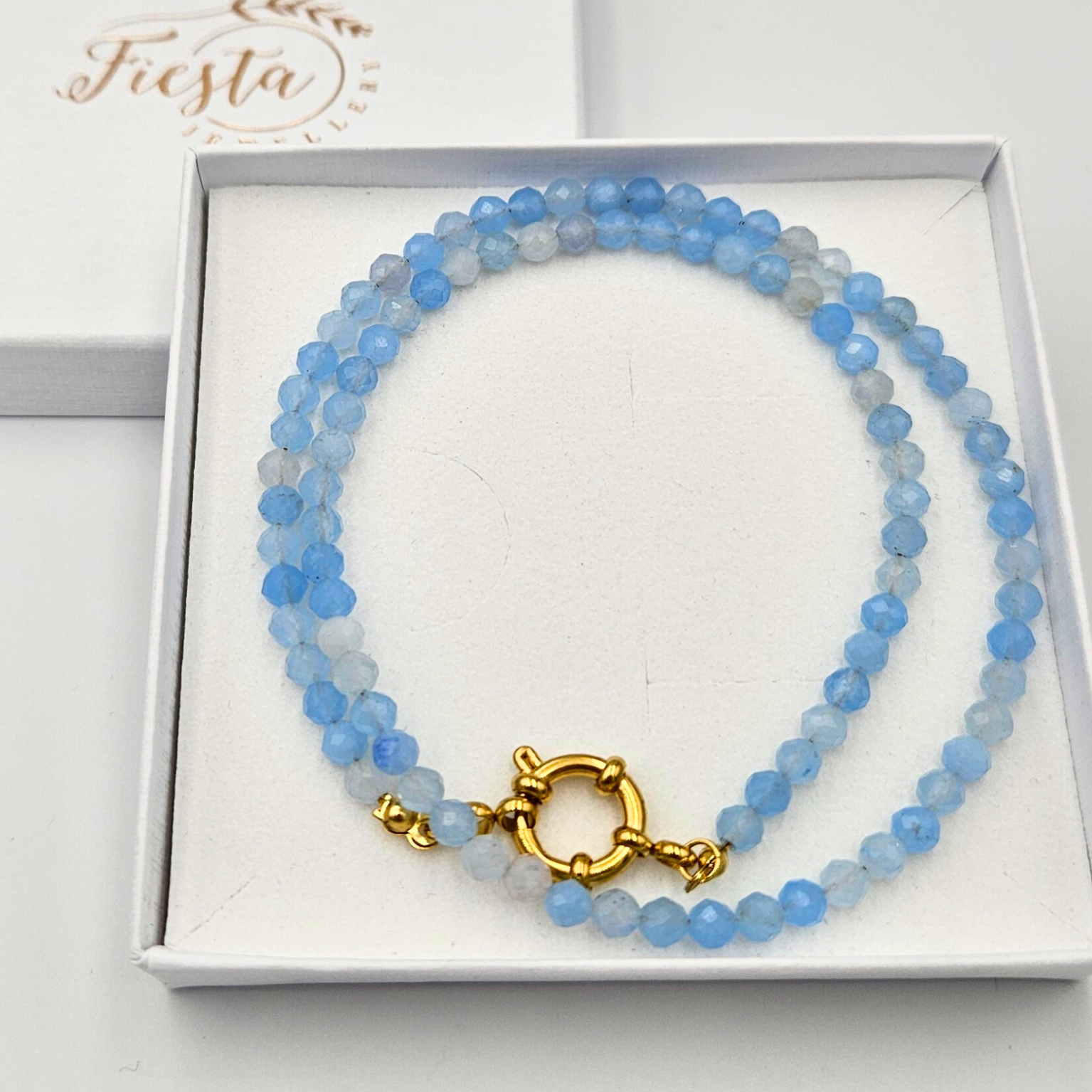 Ketting met facetgeslepen aquamarijn afgewerkt met een boeisluiting van goldplated stainless steel